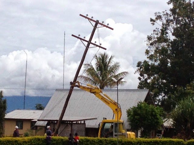 Mini track hoe standing a new power pole on the Kudjip Mission Station.